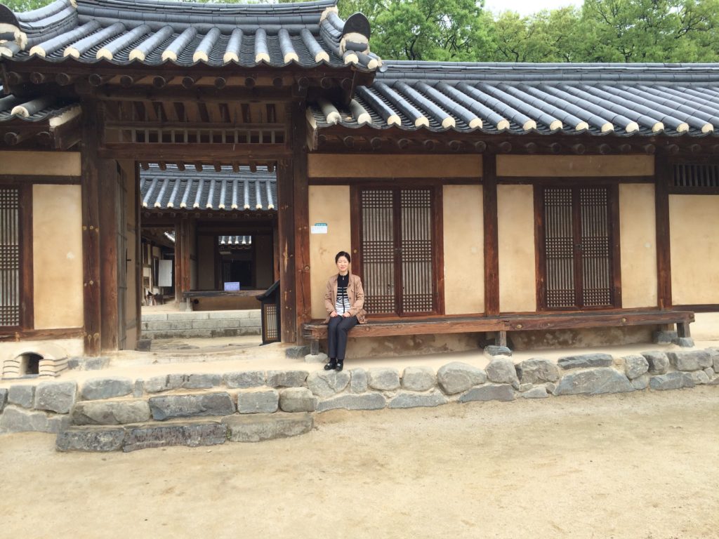 Heejoeng sitting outside a traditional royal home