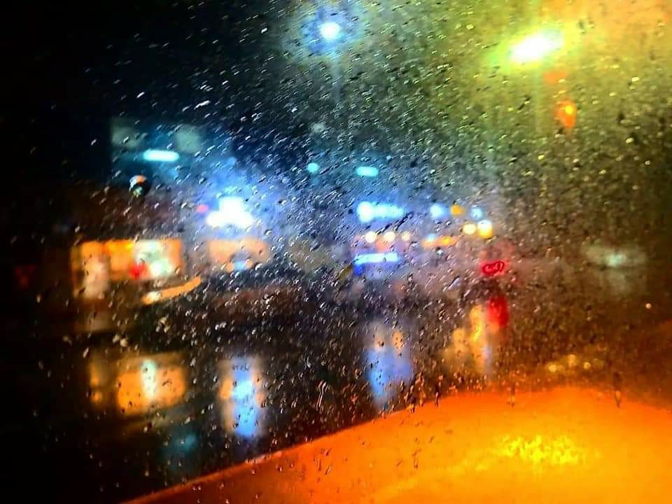 빗방울로 덮힌 창문 너머 불빛으로 가득한 도시의 밤거리 모습. 