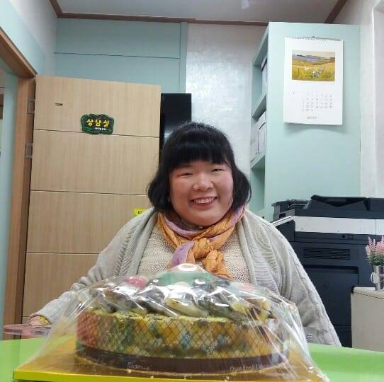 Yoonseon smiling behind a cake